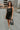 Full body view of model wearing the Brielle Black Sequin Fringe Mini Dress which features black sheer fabric, black lining, mini length, black sequin fringe details, scooped neckline, adjustable straps, sleeveless and monochrome back zippper with hook clo