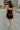 Full body back view of model wearing the Brielle Black Sequin Fringe Mini Dress which features black sheer fabric, black lining, mini length, black sequin fringe details, scooped neckline, adjustable straps, sleeveless and monochrome back zippper with hoo