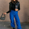 Full body front view of model wearing the Kyla Royal Parachute Cargo Pants that have dark royal breathable nylon fabric, pockets, an elastic waist with a bungee, and relaxed legs with elastic ankles and bungees.