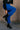 Side view of model wearing the Kyla Royal Parachute Cargo Pants that have dark royal breathable nylon fabric, pockets, an elastic waist with a bungee, and relaxed legs with elastic ankles and bungees.