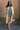 Full body view of model wearing the Sasha Grey Green Mock Neck Sweater Dress which features grey green textured knit fabric, a thick ribbed hem, mini length, a high ribbed neckline, and long sleeves with ribbed cuffs.