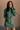 Front view of model wearing the Sasha Grey Green Mock Neck Sweater Dress which features grey green textured knit fabric, a thick ribbed hem, mini length, a high ribbed neckline, and long sleeves with ribbed cuffs.