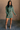 Full body view of model wearing the Sasha Grey Green Mock Neck Sweater Dress which features grey green textured knit fabric, a thick ribbed hem, mini length, a high ribbed neckline, and long sleeves with ribbed cuffs.