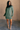 Full body view of model wearing the Sasha Grey Green Mock Neck Sweater Dress which features grey green textured knit fabric, a thick ribbed hem, mini length, a high ribbed neckline, and long sleeves with ribbed cuffs.