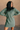 Front view of model wearing the Sasha Grey Green Mock Neck Sweater Dress which features grey green textured knit fabric, a thick ribbed hem, mini length, a high ribbed neckline, and long sleeves with ribbed cuffs.