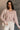 Front view of model wearing the Ada Dusty Rose Long Sleeve Top which features dusty mauve pink knit fabric, slight slits on each side, distressed details, a front left chest pocket, a v-neckline with collar, dropped shoulders, and long sleeves with cuffs.