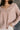 Close up view of model wearing the Ada Dusty Rose Long Sleeve Top which features dusty mauve pink knit fabric, slight slits on each side, distressed details, a front left chest pocket, a v-neckline with collar, dropped shoulders, and long sleeves with cuf
