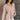Side view of model wearing the Ada Dusty Rose Long Sleeve Top which features dusty mauve pink knit fabric, slight slits on each side, distressed details, a front left chest pocket, a v-neckline with collar, dropped shoulders, and long sleeves with cuffs.