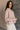 Side view of model wearing the Ada Dusty Rose Long Sleeve Top which features dusty mauve pink knit fabric, slight slits on each side, distressed details, a front left chest pocket, a v-neckline with collar, dropped shoulders, and long sleeves with cuffs.