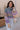 Front view of model wearing the Eliza Purple Multi Long Sleeve Sweater which features purple, peach, cream blue and teal grey knit fabric, a floral and striped pattern, a loose turtle neckline, dropped shoulders, and long balloon sleeves with ribbed cuffs