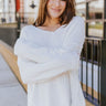 Front view of model wearing the Winter Wonderland Sweater that has white popcorn knit fabric, a v-neckline, dropped shoulders, and long sleeves with ribbed wrists.