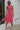 Front view of model wearing the Lost Without You Midi Dress that has a red and pink geometric pattern, a tiered skirt with a midi-length hem, and a draped neck that ties in the back.