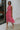 Front view of model wearing the Lost Without You Midi Dress that has a red and pink geometric pattern, a tiered skirt with a midi-length hem, and a draped neck that ties in the back.