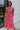 Front view of model wearing the Lost Without You Midi Dress that has a red and pink geometric pattern, a tiered skirt with a midi-length hem, and a draped neck that ties in the back.