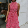 Front view of model wearing the Lost Without You Midi Dress that has a red and pink geometric pattern, a tiered skirt with a midi-length hem, and a draped neck that ties in the back.