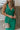 Close front view of model wearing the Make You Mine Midi Dress that has green plisse fabric, a midi-length hem, a v neck, thick straps, a sleeveless body, and a back zipper with a hook closure.