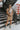 Full body front view of model wearing the Now Or Never Dress that has mocha ribbed fabric, a mini-length hem, a scoop neckline, adjustable double spaghetti straps, and a built-in bra