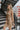 Frontal side view of model wearing the Now Or Never Dress that has mocha ribbed fabric, a mini-length hem, a scoop neckline, adjustable double spaghetti straps, and a built-in bra