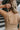 Upper back view of model wearing the Now Or Never Dress that has mocha ribbed fabric, a mini-length hem, a scoop neckline, adjustable double spaghetti straps, and a built-in bra