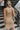 Back view of model wearing the Now Or Never Dress that has mocha ribbed fabric, a mini-length hem, a scoop neckline, adjustable double spaghetti straps, and a built-in bra
