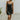 Full body front view of model wearing the Traveler Mini Dress in Black that has lightweight fabric, a mini-length hem, shorts lining with side pockets, bra padding, a scoop neck, and straps that cross in the back.