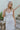 Front view of model wearing the Now and Forever Dress that has white fabric, a mini-length hem, a white lining, a round neckline, ruffle/elastic straps and a monochromatic side zipper.