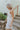 Side view of model wearing the Now and Forever Dress that has white fabric, a mini-length hem, a white lining, a round neckline, ruffle/elastic straps and a monochromatic side zipper.