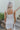 Back view of model wearing the Now and Forever Dress that has white fabric, a mini-length hem, a white lining, a round neckline, ruffle/elastic straps and a monochromatic side zipper.