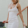 Front view of model wearing the Now and Forever Dress that has white fabric, a mini-length hem, a white lining, a round neckline, ruffle/elastic straps and a monochromatic side zipper.