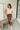 Full body front view of model wearing the Trouble Maker Pleather Midi Skirt that has dark brown faux leather, midi length, a slit, pockets, a front zipper, and belt loops