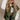 Front view of model wearing the Big Sky Olive Green Oversized Puffer Vest which features olive green lightweight puffer fabric, an elastic hem, two front pockets, a monochromatic front zipper, a high neckline, and a sleeveless design.