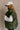 Close up side view of model wearing the Big Sky Olive Green Oversized Puffer Vest which features olive green lightweight puffer fabric, an elastic hem, two front pockets, a monochromatic front zipper, a high neckline, and a sleeveless design.