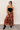 Full body view of model wearing the Catalina Rust Multi Floral Maxi Skirt which features rust sheer fabric with mustard, blue, green, pink and white floral print, metallic thread details, rust lining, midi length, an elastic waistband, belt loops, and a t