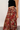 Close up view of model wearing the Catalina Rust Multi Floral Maxi Skirt which features rust sheer fabric with mustard, blue, green, pink and white floral print, metallic thread details, rust lining, midi length, an elastic waistband, belt loops, and a ti