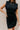 Front view of model wearing the Reese Black Sweater Sleeveless Dress features black knit fabric, mini length, belt loops with a tie around the waist, a high neckline, and a sleeveless design with padded shoulders.