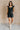 Full body view of model wearing the Avril Black Denim Ruffle Sleeveless Romper which features black washed denim fabric, pockets on each side, a front zip up, an elastic waistband, a square neckline, and ruffle straps.