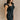 Front side view of model wearing the Avril Black Denim Ruffle Sleeveless Romper which features black washed denim fabric, pockets on each side, a front zip up, an elastic waistband, a square neckline, and ruffle straps.