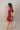Full body side view of model wearing the Willow Burgundy Puff Sleeve Dress that has burgundy fabric, mini length, a tiered skirt, smocked chest, a square neck and short puff sleeves
