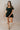 Full body front view of model wearing the Eliana Black Tiered Short Sleeve Romper that has black lightweight fabric, a ruffle-tiered skirt, black shorts lining, an elastic waistband, a sweetheart neckline and short puff sleeves.