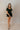 Full body front view of model wearing the Eliana Black Tiered Short Sleeve Romper that has black lightweight fabric, a ruffle-tiered skirt, black shorts lining, an elastic waistband, a sweetheart neckline and short puff sleeves.