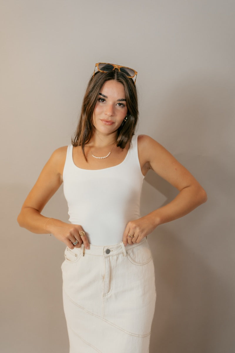Upper front view of model wearing the Esther Cream Denim Midi Skirt that has cream denim fabric with brown stitched geometric pattern, belt loops, and pockets.