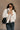 Front view of model wearing the Piper Off White Sherpa & Corduroy Jacket that has sherpa fabric, corduroy details, front snaps with a zipper, a high neck, pockets, and long sleeves.