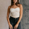 Front view of model wearing the Krista Cream Velvet Strapless Tube Top which features cream velvet fabric, a cropped waist, ruched side details, and a strapless sweetheart neckline.