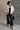 Full body front view of model wearing the view of model wearing the Piper Off White Sherpa & Corduroy Jacket that has sherpa fabric, corduroy details, front snaps with a zipper, a high neck, pockets, and long sleeves.