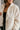 Close front view of model wearing the view of model wearing the Piper Off White Sherpa & Corduroy Jacket that has sherpa fabric, corduroy details, front snaps with a zipper, a high neck, pockets, and long sleeves.