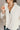 Close front view of model wearing the view of model wearing the Piper Off White Sherpa & Corduroy Jacket that has sherpa fabric, corduroy details, front snaps with a zipper, a high neck, pockets, and long sleeves.