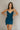 front view of model wearing the Tinsley Teal Sleeveless Mini Dress that has dark teal lightweight fabric, an overlapped faux-wrap skirt, a surplice neck, adjustable straps, and a back zipper.