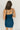 Back view of model wearing the Tinsley Teal Sleeveless Mini Dress that has dark teal lightweight fabric, an overlapped faux-wrap skirt, a surplice neck, adjustable straps, and a back zipper.