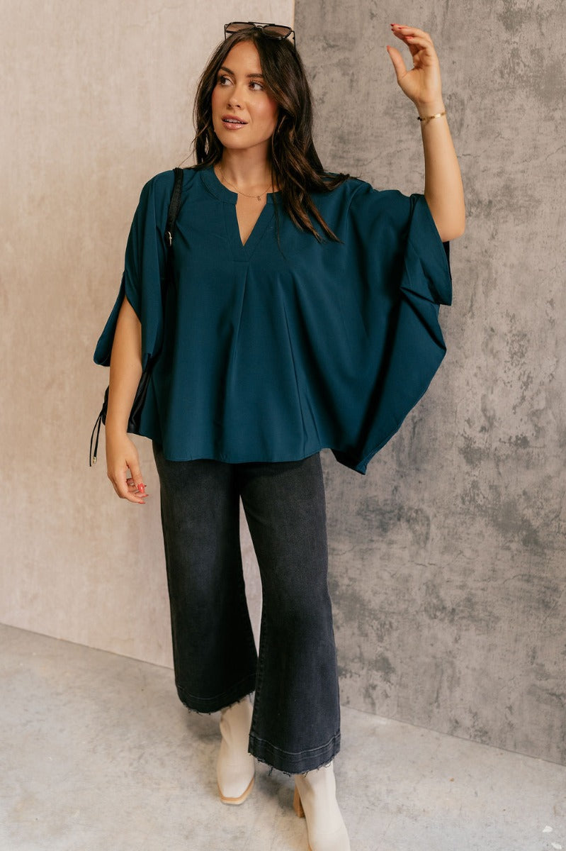 Full body view of model wearing the Grace Teal Oversized Short Sleeve Top which features teal lightweight fabric, an oversized fit, a round neckline with a v-cutout, and short dolman sleeves.