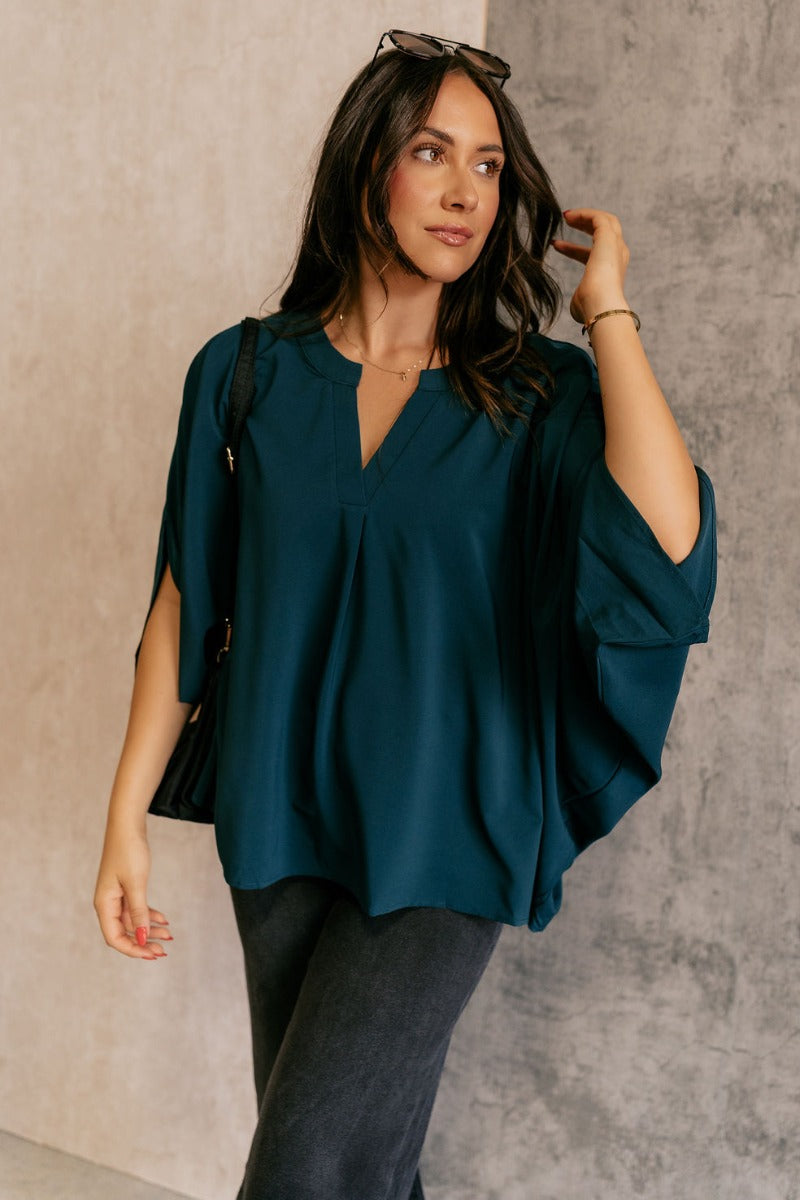 Front view of model wearing the Grace Teal Oversized Short Sleeve Top which features teal lightweight fabric, an oversized fit, a round neckline with a v-cutout, and short dolman sleeves.